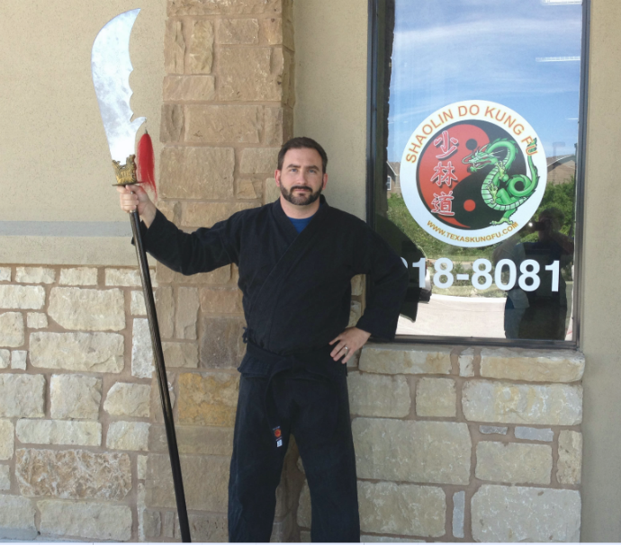 Don in a martial arts uniform (gi), holding a Kwan Dao - giant sword affixed to a long pole